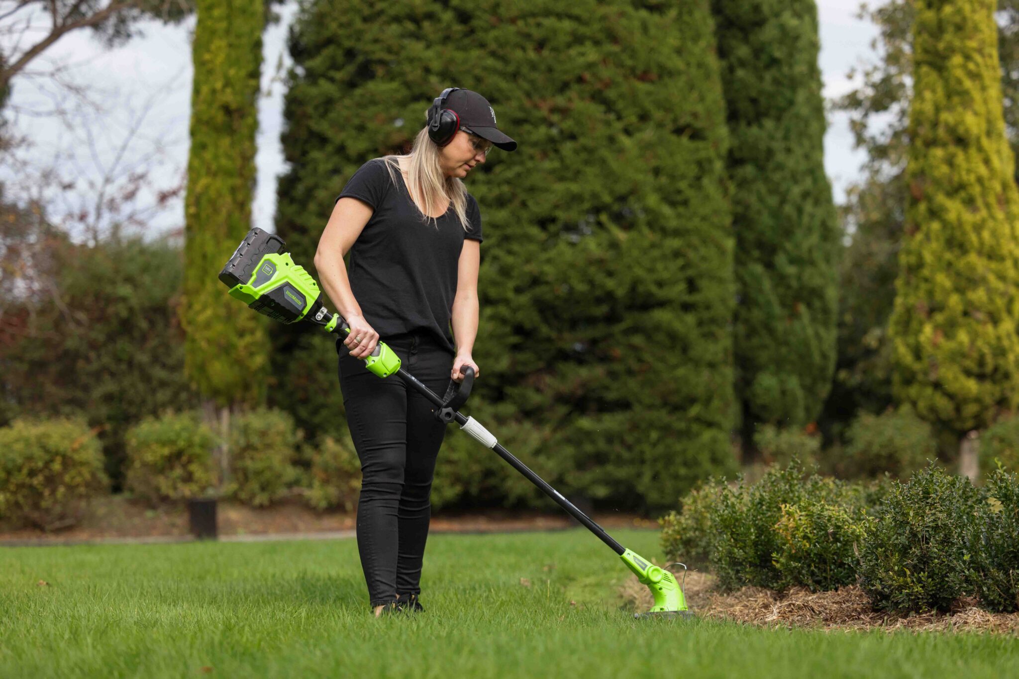 Woman using brushcutter line trimmer tool in garden setting